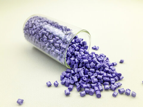 Violet pearl masterbatch granules in a glass tube on a white background, this polymer is a colorant for products in the plastics industry