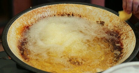 Frying food inside large boiling frying pan with oil