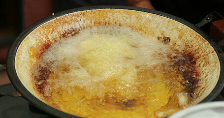 Frying food inside large boiling frying pan with oil