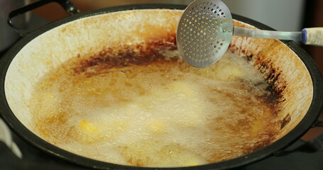 cooking traditional polenta frita inside large frying pan with oil