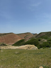 A green hillside with red mountains and a blue sky in David Gareja in Georgia