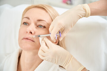 Woman visiting cosmetologist to make lip augmentation and correction