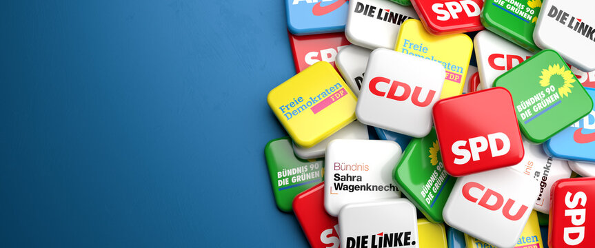 Logos of the biggest German nationwide operating political parties (CDU, SPD, Die Gr&uuml;nen, FDP, Die Linke, BSW, AfD) on a heap on a table.