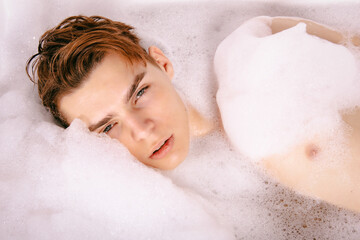 A young attractive man is washing himself in the bathroom. 