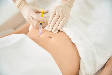 Cosmetologist making injections of plasma into client belly