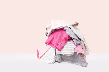 Stack of pink dirty clothes waiting for laundry isolated on light beige background
