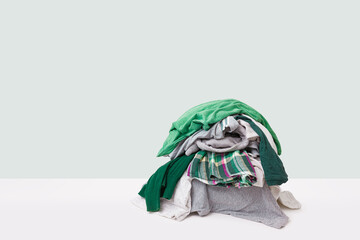 Stack of dirty clothes waiting for laundry isolated on light green background