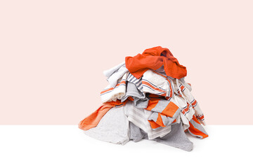 Stack of orange dirty clothes waiting for laundry isolated on light beige background