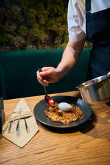 Cropped male chef adding kiwis and cherries in jam to frying waffle on plate