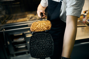 Selective focus of partial male chef holding frying pancake in pancake maker