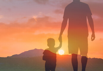 Father's and his son holding hands walking at sunset . Dad leading son over summer nature outdoor....