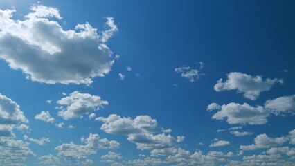 Clouds running across the blue sky. White puffy and fluffy clouds on blue sky. Time lapse.