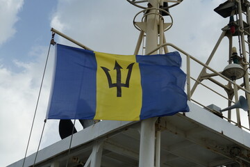 Flying Barbados flag, vertical triband of ultramarine and gold with the black trident-head, on the...