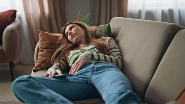 Sleepy woman resting couch holding mobile phone close up. Bored girl lying sofa