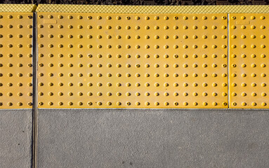Yellow warning tile bumps in front of train tracks