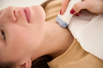 Close up partial of doctor doing ultrasound scanning of woman thyroid gland
