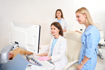 Obraz premium Doctor doing ultrasound scanning of woman belly while colleagues looking at it