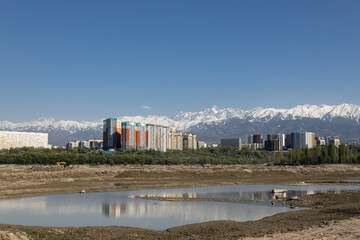Urban landscape, modern buildings rise against the awe-inspiring backdrop of snow-capped mountains....