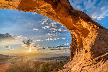 The low sun illuminating the arch rock from below reveals intricate details at Partition Arch in...