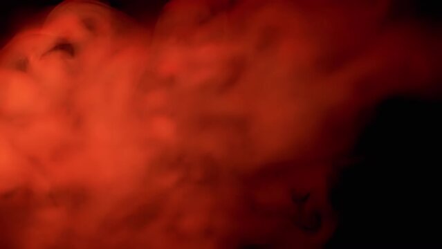 Explosion of Red Smoke or Vapor on Black Blurred Background. Abstract. Side view. Flash. Soft puffs of smoke or steam mix chaotically on empty space. Flash. Passing smoke, tail. Particle explosion.