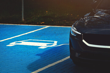 EV parking and charging station with electric vehicle. blue painted cobblestone surface and white...
