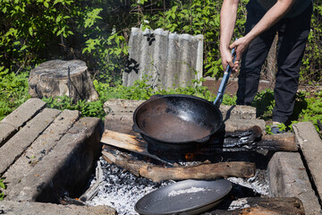 Firing cast iron pasta over a fire. Processing cast iron at the stake