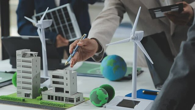 Business people having consultation about wind energy at company office. Business team discussing about windmill and alternative green enery. Net zero and carbon neutral concept