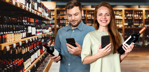 Happy young adult couple buying wine in liquor store. Customers use mobile phone while shopping in supermarket.