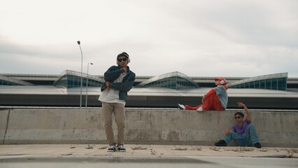 Handsome break dancer enjoy perform freestyle movement with asian friend cheering behind. Hipster...