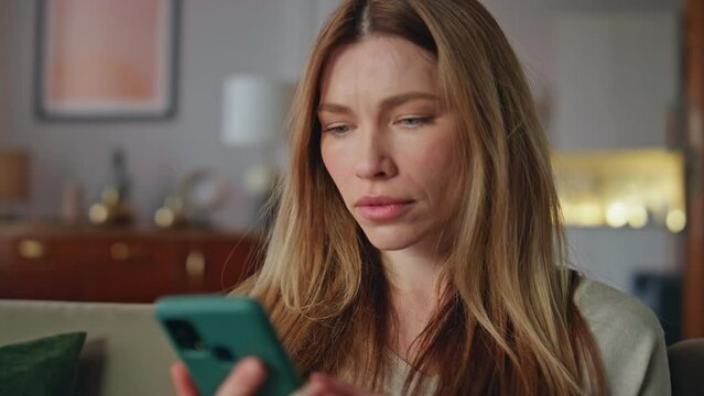 Shocked girl looking mobile phone in home closeup. Woman reading smartphone