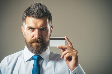 Handsome bearded man in white shirt and blue tie showing credit card with magnetic stripe. Copy...