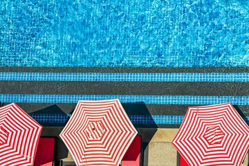 Red and white striped umbrellas along sparkling pool embody resort luxury, offering idyllic escape...