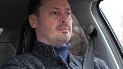Confident bearded man driving car automobile closeup face. Pensive male driver riding vehicle...