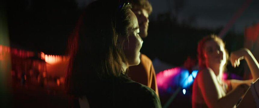 Diverse group of young adults dancing and cheering at a music festival at night