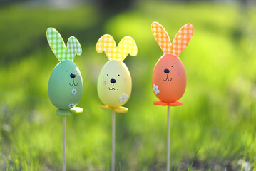 Easter background. Multi-colored Easter eggs - bunnies on the grass in the garden