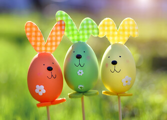 Easter background. Multi-colored Easter eggs - bunnies on the grass in the garden