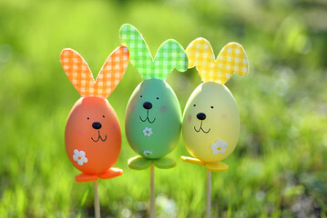 Easter background. Multi-colored Easter eggs - bunnies on the grass in the garden