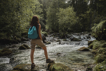 A woman hiking in the nature along the mountain river in Austria.