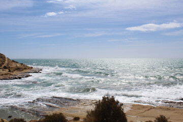 Fototapeta na wymiar natural background of sky, sea and rocks, Mediterranean coast in Spain, waves crashing on the beach
