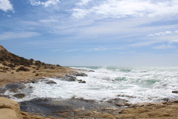 Fototapeta na wymiar waves on the beach, natural background of sky, sea and rocks, Mediterranean coast in Spain