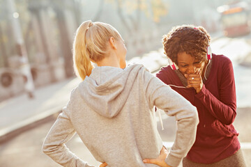 Two women jogging together with headphones in an urban park