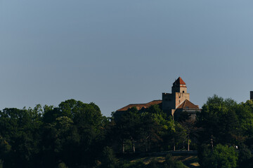 An old stone castle with a tiled roof on the territory of the Kalemegdan Fortress Park in the center of the old town. Green spring trees grow all around. Belgrade, Serbia.