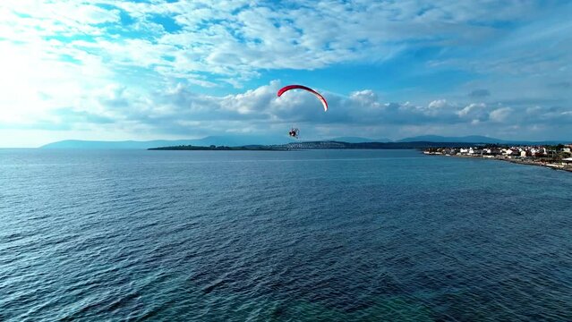 Close-up of a paramotor tricycle suspended under a parachute in the air. Drone shooting of man with paramotor flying in the air