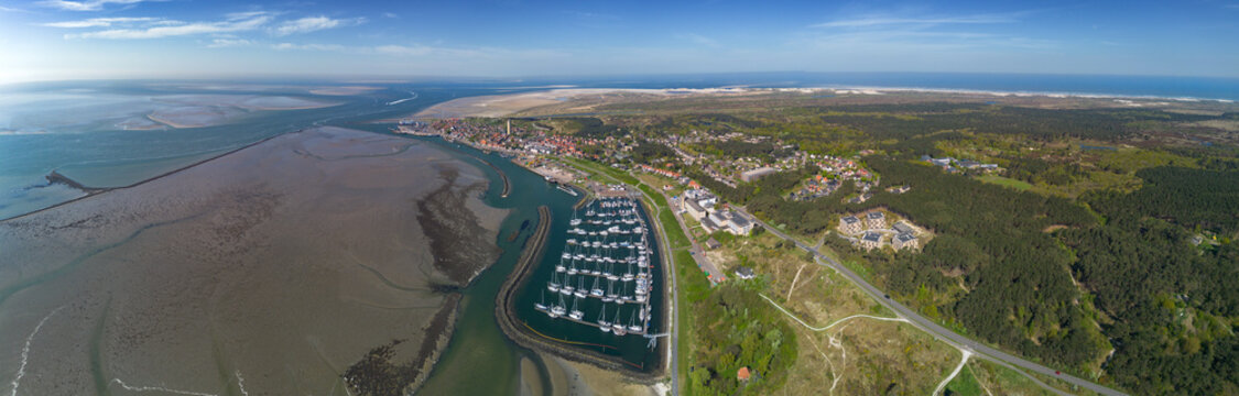 Aerial drone image of the historic Frisian town of West Terschelling on the Wad island in world heritage site Wadden Sea. Old brick lighthouse Brandaris and marina with dunes, sandbanks and tidal sea 