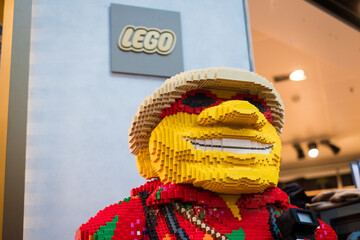 Naklejka premium Copenhagen, Denmark - April 7, 2024: Huge Lego sculpture of a smiling man at the Lego shop in Copenhagen Airport. Legos are interlocking plastic bricks.