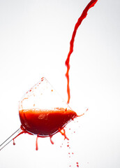 Splash in the glass, transparent glass receiving orange liquid, white background, selective focus