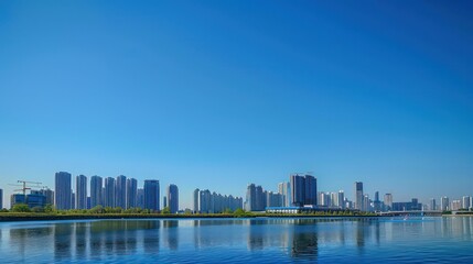 Peaceful scenery of a city's skyline with serene water in the foreground under a vast blue sky