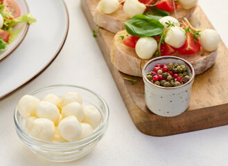 Mozzarella balls in glass bowl on a white background