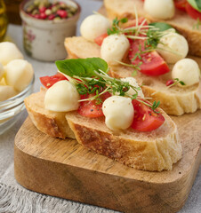 Round mozzarella, cherry tomatoes and microgreens on a piece of white bread, a healthy sandwich