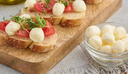 Round mozzarella, cherry tomatoes and microgreens on a piece of white bread, a healthy sandwich